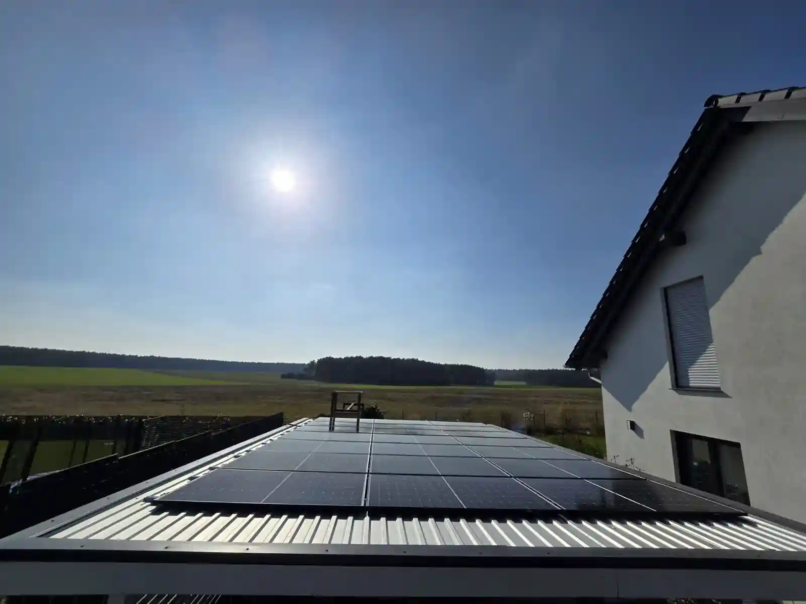 PV-Anlage auf einem flachen Blechdach PV-Anlage auf einem flachen Blechdach, im Vordergrund offenes Feld und helle Sonne am Himmel. Komplette Photovoltaikanlage inkl. Montage und Anmeldung Solarfirma in der Nähe mit Montage und Anmeldung. Solarfirma in der Nähe Ihres Wohnorts