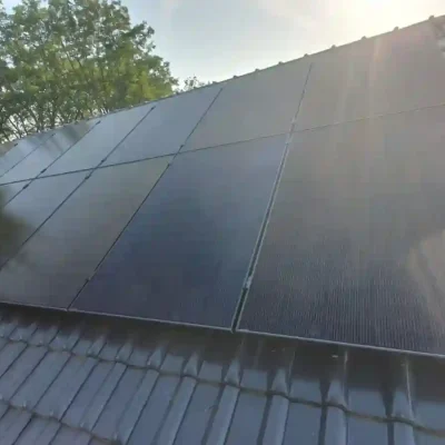 Solarpanels auf einem graublauen Dach, starker Sonnenlichteinfall von rechts erzeugt Lensflare.