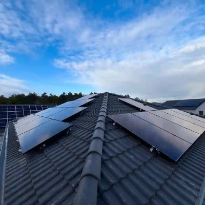 PV-Anlage auf beiden Seiten eines Satteldachs mit grauen Dachpfannen, Baustellengerüst und Nachbarhäuser sichtbar. Die Komplette Photovoltaikanlage inkl. Montage und Anmeldung