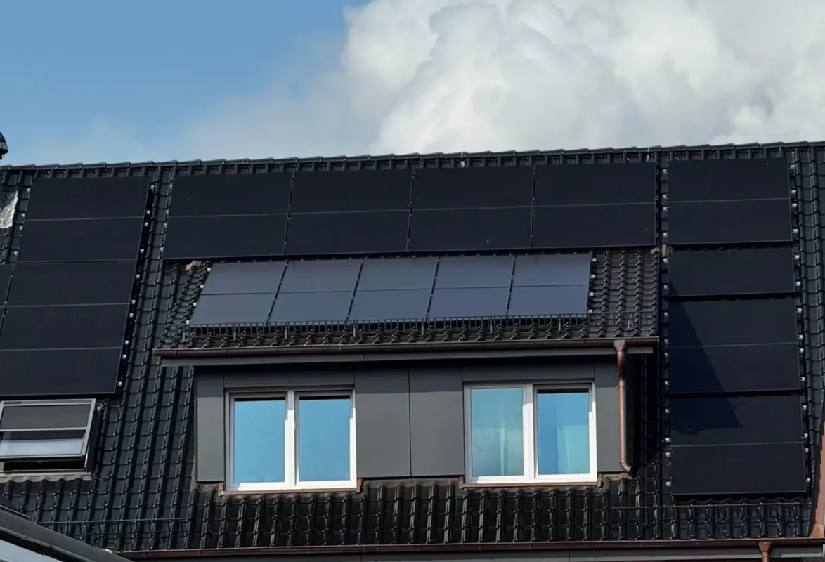 Das Bild zeigt die Dachfläche eines Hauses, die mit zahlreichen Photovoltaikmodulen ausgestattet ist. Die PV-Module sind gleichmäßig auf den dunklen Dachziegeln installiert und decken fast die gesamte Dachfläche ab. Besonders auffällig ist der PV Reinigungseffekt, da die Module durch ihre saubere Oberfläche gleichmäßig dunkel glänzen und so eine hohe Energieeffizienz gewährleisten. Saubere Solarmodule reflektieren weniger Schmutz und Staub, was den Stromertrag deutlich verbessert.