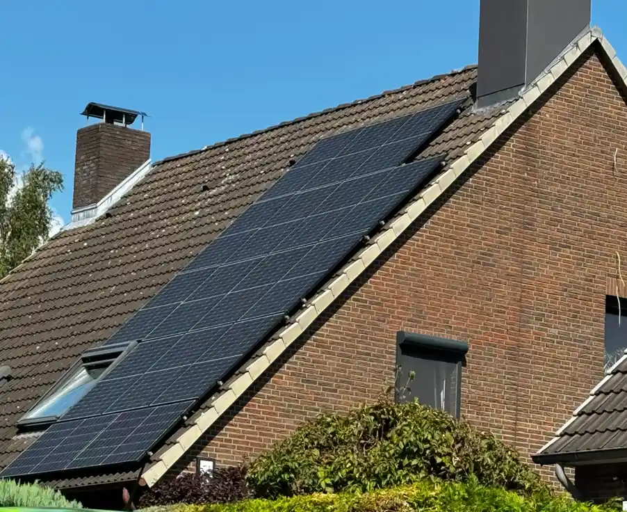 Auf dem Ziegeldach eines Einfamilienhauses ist eine moderne Photovoltaikanlage installiert. Mehrere schwarze Solarmodule sind in Südausrichtung montiert und fügen sich harmonisch in die Dachfläche ein. Das Bild zeigt ein typisches Beispiel dafür, wie eine Anlage optisch integriert wird und welchen Platzbedarf sie hat – eine wichtige Information für alle, die sich fragen: Was kostet eine Photovoltaikanlage für ein Eigenheim.